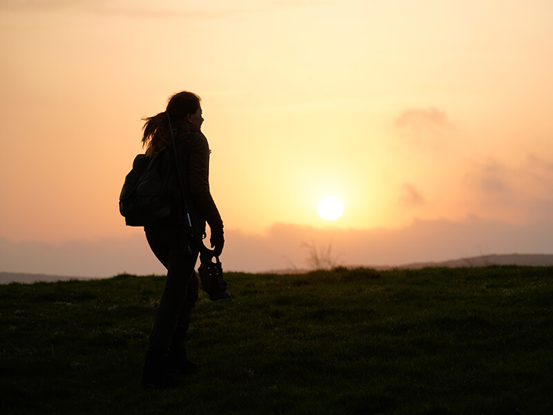 The silhouette of a female hunter stands out against the sunset on the Scottish Isle of Bute